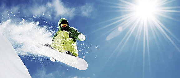 Snowboarder en plein saut avec des rayons de soleil
